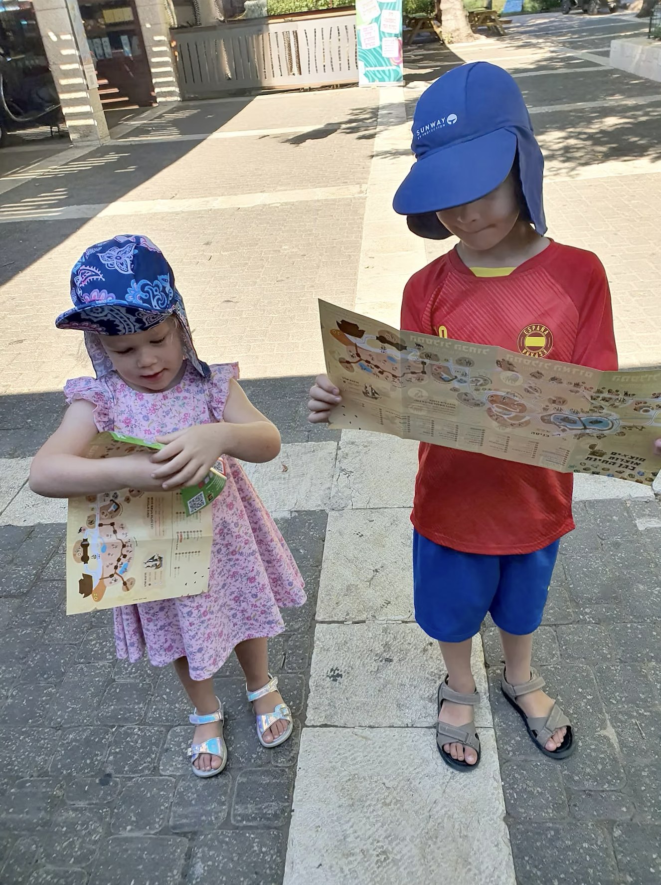שני ילדים בכובעי שמש מחזיקים את המפה המודפסת בגן